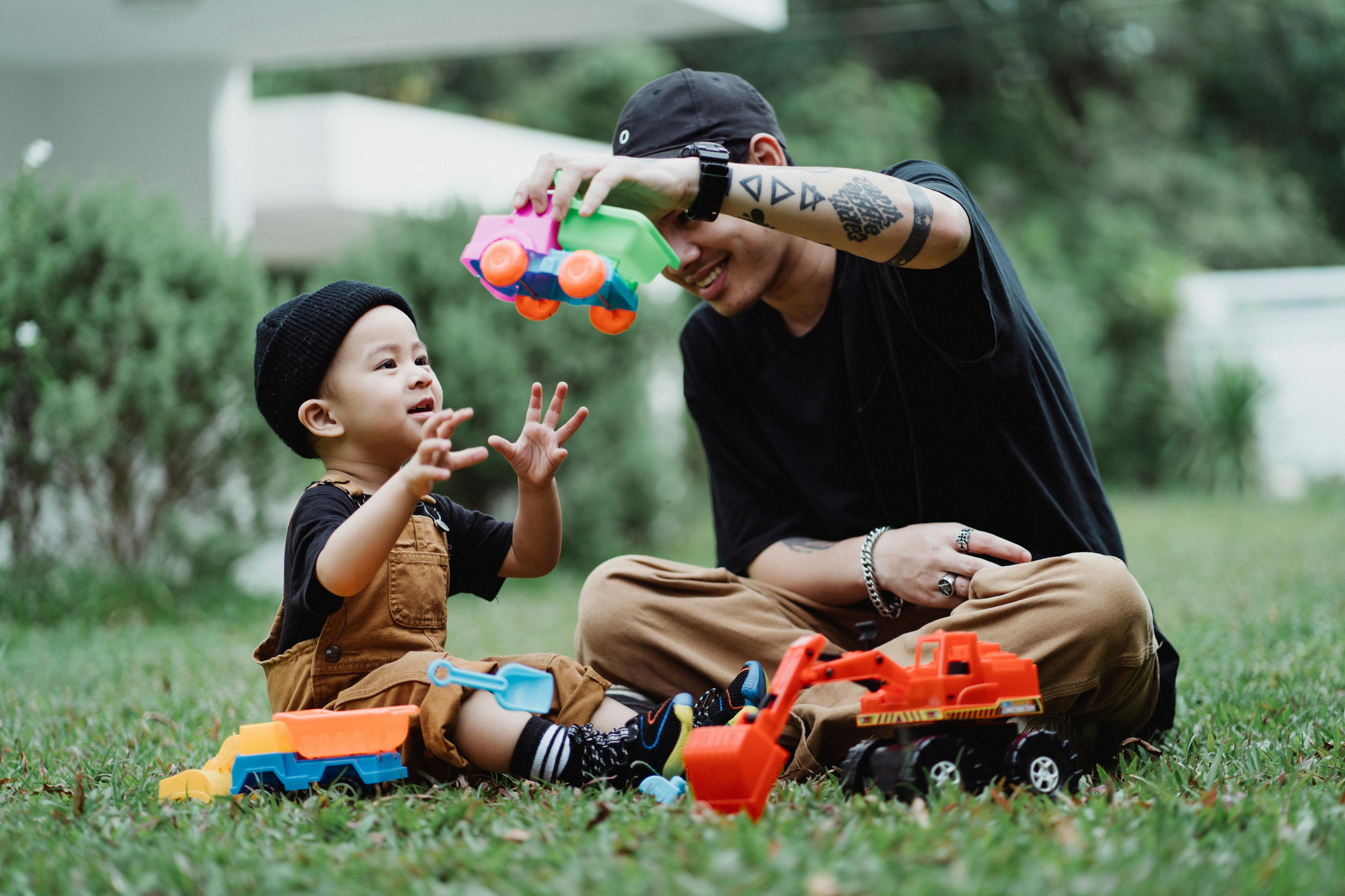2025 男神月促銷頁面插圖 4 Father and Son Playing with Toy Cars Outdoors - Ketut Subiyanto